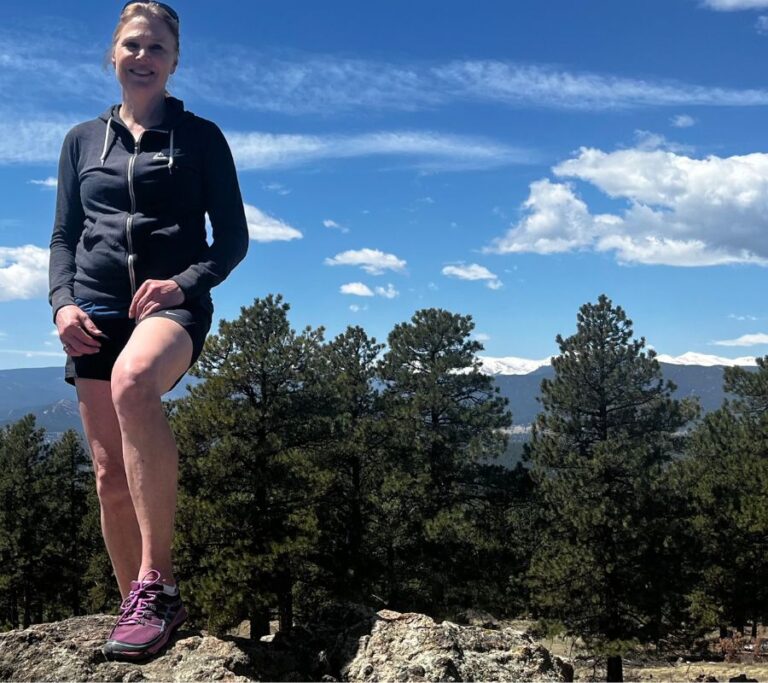 Stacey standing on a rock on the mountains after recovering from chronic pain.